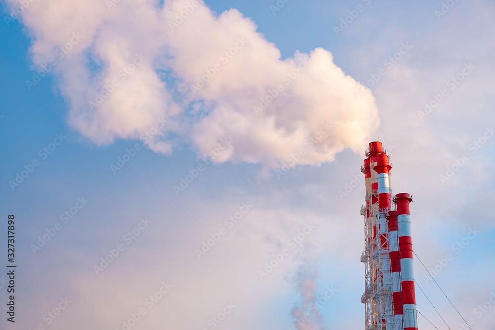 Smokestacks against a clear blue sky. Smoke from the pipes of thermal power plants that supply heat to the city. Pipes of factories. Environmental issues and the concept of global warming Smokestacks against a clear blue sky. Smoke from the pipes of thermal power plants that supply heat to the city. Pipes of factories. Environmental issues and the concept of global warming