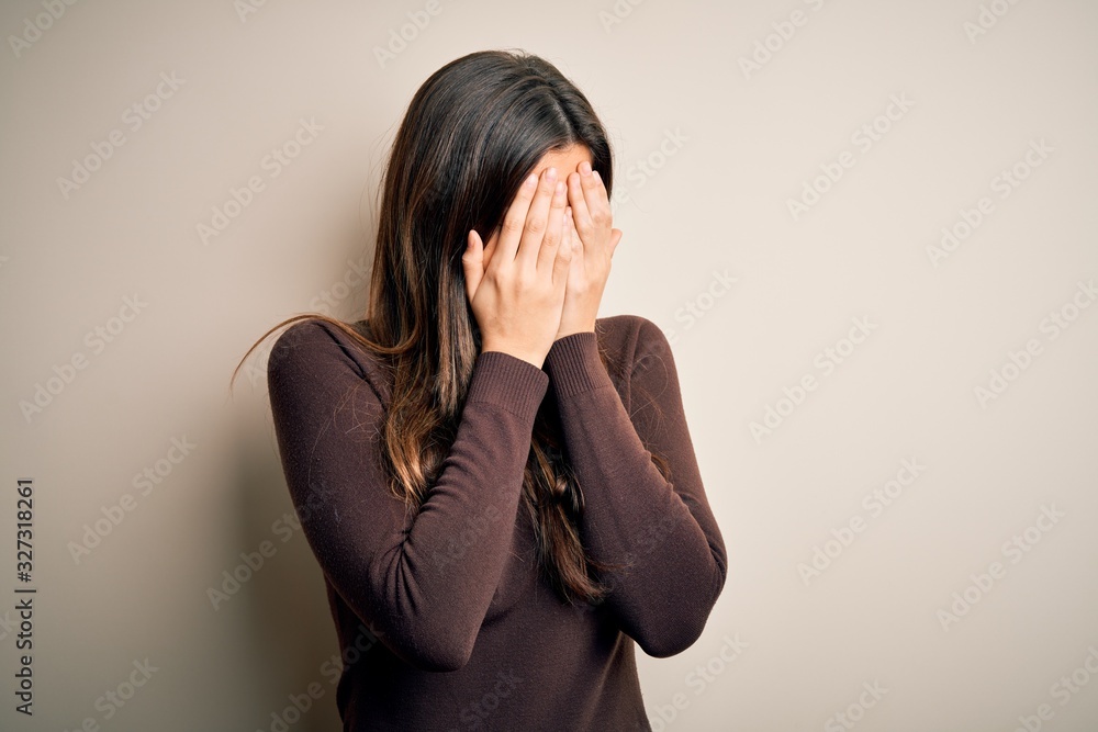 Young beautiful girl wearing casual sweater standing over isolated white background with sad expression covering face with hands while crying. Depression concept. Young beautiful girl wearing casual sweater standing over isolated white background with sad expression covering face with hands while crying. Depression concept.