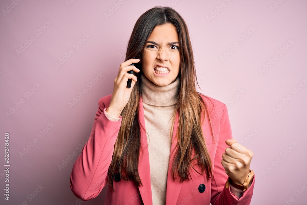 Young beautiful girl having conversation talking on the smartphone over white background annoyed and frustrated shouting with anger, crazy and yelling with raised hand, anger concept Young beautiful girl having conversation talking on the smartphone over white background annoyed and frustrated shouting with anger, crazy and yelling with raised hand, anger concept