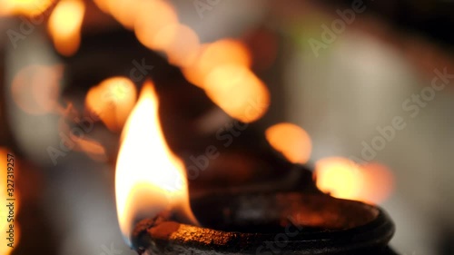 Closeup 4k video of long row of burning oil lamps with sacred fire at hindu temple photo