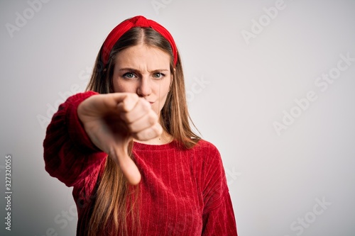 Young beautiful redhead woman wearing red casual sweater and diadem over yellow background looking unhappy and angry showing rejection and negative with thumbs down gesture. Bad expression. © Krakenimages.com