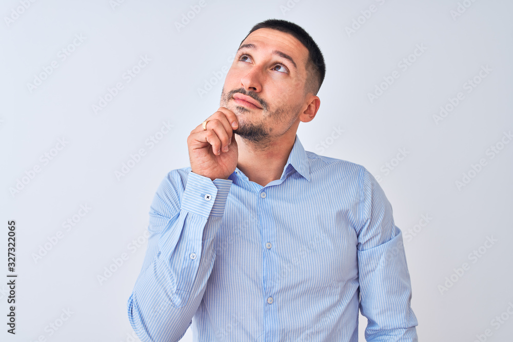 Young handsome business man standing over isolated background with hand on chin thinking about question, pensive expression. Smiling with thoughtful face. Doubt concept. Young handsome business man standing over isolated background with hand on chin thinking about question, pensive expression. Smiling with thoughtful face. Doubt concept.