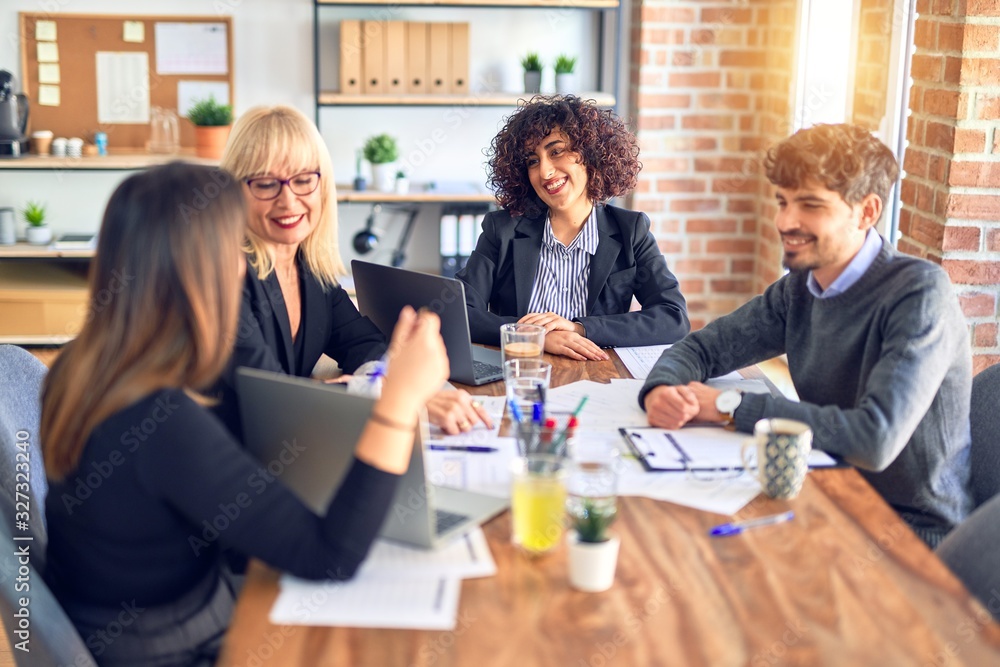 Group of business workers smiling happy and confident. Working together with smile on face using laptop and speaking at the office Group of business workers smiling happy and confident. Working together with smile on face using laptop and speaking at the office