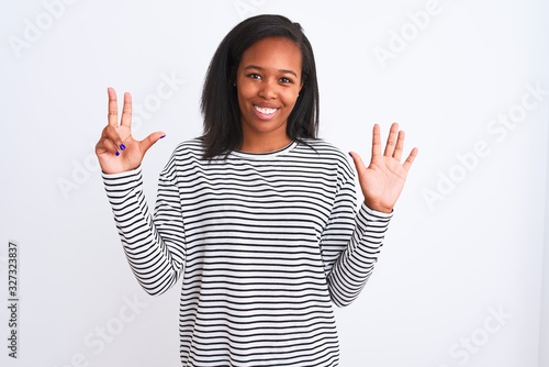 Beautiful young african american woman wearing winter sweater over isolated background showing and pointing up with fingers number eight while smiling confident and happy. © Krakenimages.com