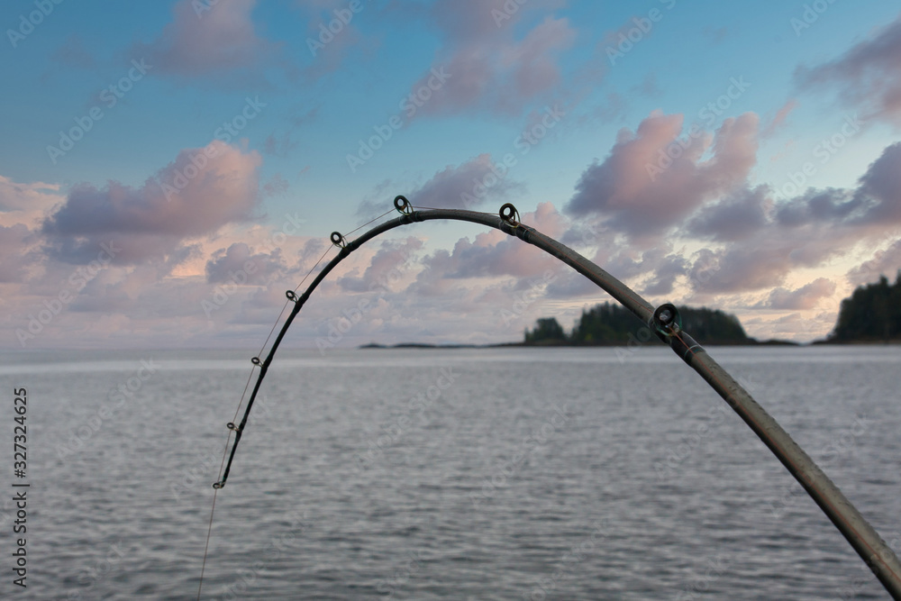 A fishing pole bent with a fish on the line Stock Photo