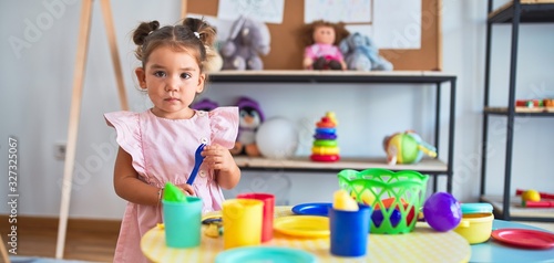 Young beautiful toddler playing with cutlery and food toys on the table at kindergaten photo