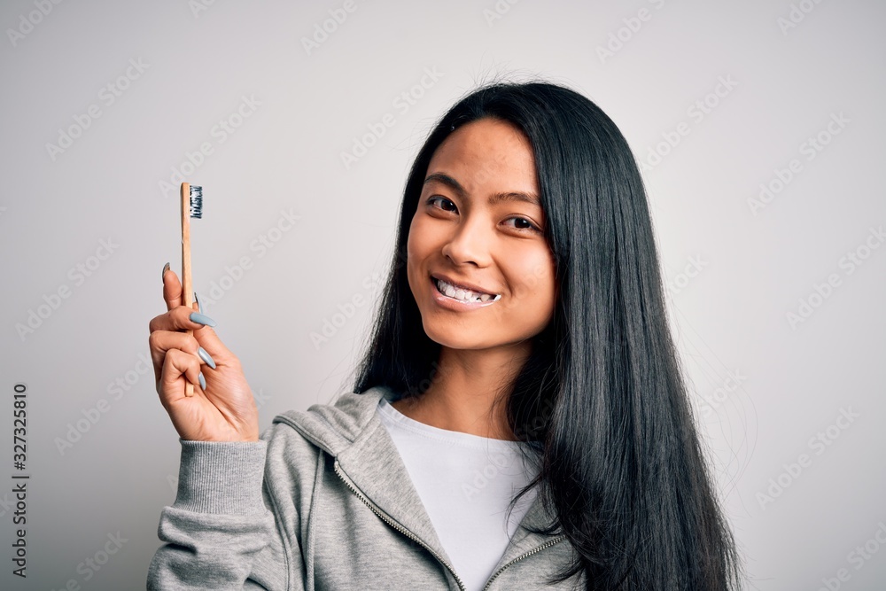 Young beautiful woman smiling happy. Standing with smile on face whasing tooth using toothbrush over isolated white background Young beautiful woman smiling happy. Standing with smile on face whasing tooth using toothbrush over isolated white background