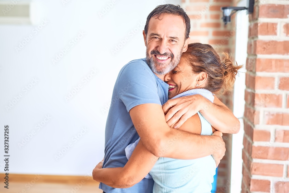 Middle age beautiful sporty couple smiling happy. Standing with smile on face hugging at gym Middle age beautiful sporty couple smiling happy. Standing with smile on face hugging at gym