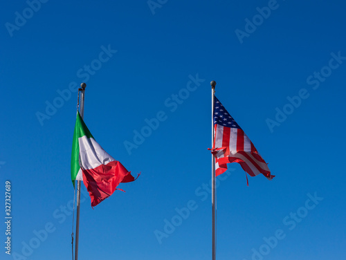 National flags of Italy and United States fluttering on background of blue sky