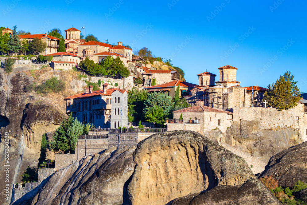 Greece. Meteora's Monasteries in the mountains in Greece. Orthodox shrine. Amazing churches on the rocks. Buildings with red roofs in the mountains. The monastery of Meteor on background of blue sky.