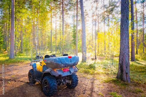 ATV stands in the woods without a driver. Active rest in the fresh air. Journey through the forest on a Quad bike. Sale and rent of ATV. Transport for off-road driving.