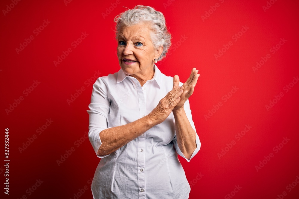 Senior beautiful woman wearing elegant shirt standing over isolated red background clapping and applauding happy and joyful, smiling proud hands together Senior beautiful woman wearing elegant shirt standing over isolated red background clapping and applauding happy and joyful, smiling proud hands together