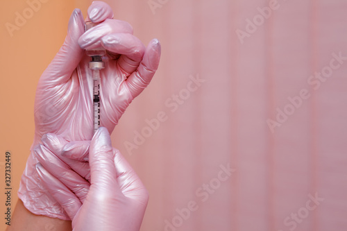 A doctor in pink gloves holds a syringe in his hand and draws medicine into it. A nurse in pink gloves at the clinic injects the patient for recovery. botox injection. Cosmetology, doctor, injection