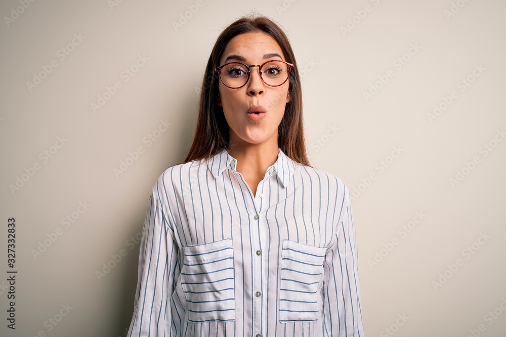 Young beautiful brunette woman wearing casual shirt and glasses over white background afraid and shocked with surprise expression, fear and excited face.