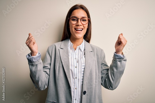 Wallpaper Mural Young beautiful brunette businesswoman wearing jacket and glasses over white background celebrating surprised and amazed for success with arms raised and open eyes. Winner concept. Torontodigital.ca