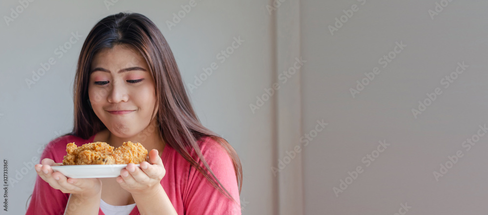 Panoramic banner copy space. asian young pretty woman slim body smiling and holding delicious crispy fried chicken on dish in kitchen at home, junk food, unhealthy food, dieting, weight loss concept Panoramic banner copy space. asian young pretty woman slim body smiling and holding delicious crispy fried chicken on dish in kitchen at home, junk food, unhealthy food, dieting, weight loss concept