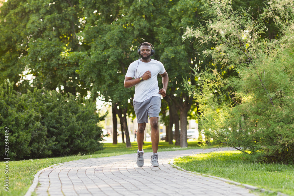 Fototapeta premium Sporty african guy is jogging in the park