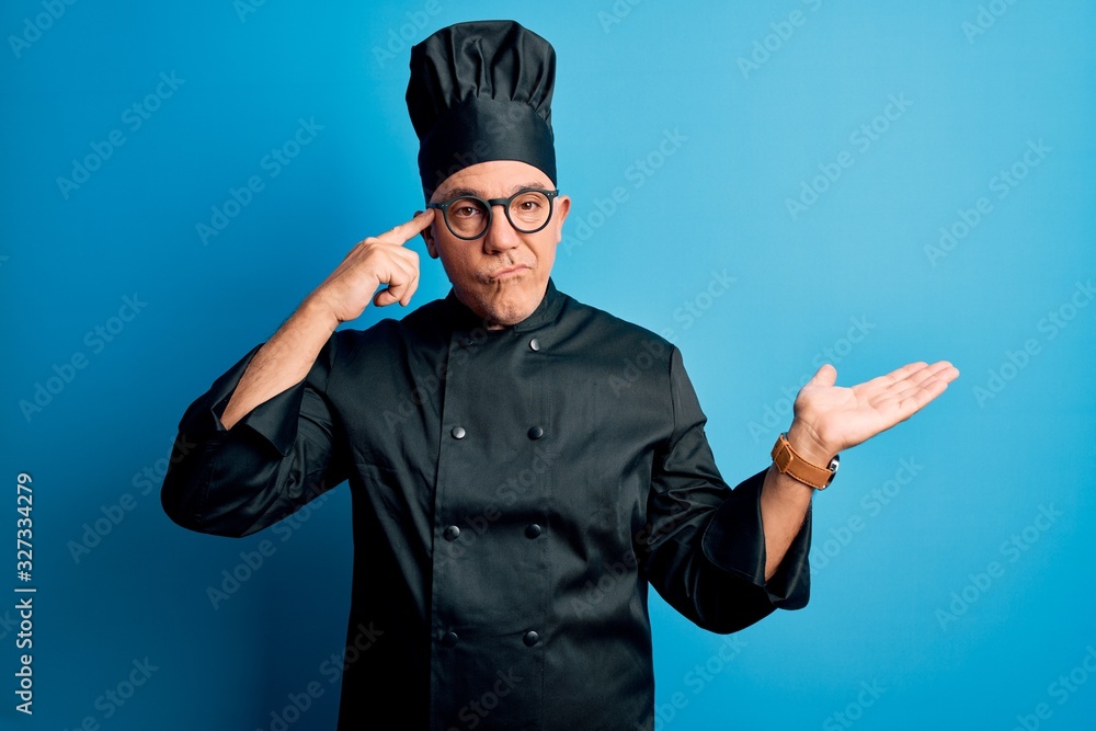 Middle age handsome grey-haired chef man wearing cooker uniform and hat confused and annoyed with open palm showing copy space and pointing finger to forehead. Think about it. Middle age handsome grey-haired chef man wearing cooker uniform and hat confused and annoyed with open palm showing copy space and pointing finger to forehead. Think about it.