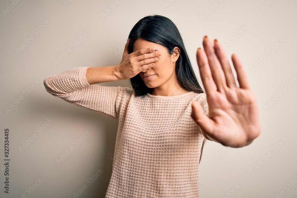 Young beautiful hispanic woman wearing elegant pink sweater over isolated background covering eyes with hands and doing stop gesture with sad and fear expression. Embarrassed and negative concept. Young beautiful hispanic woman wearing elegant pink sweater over isolated background covering eyes with hands and doing stop gesture with sad and fear expression. Embarrassed and negative concept.