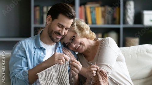 Smiling mature mom and adult son knitting together