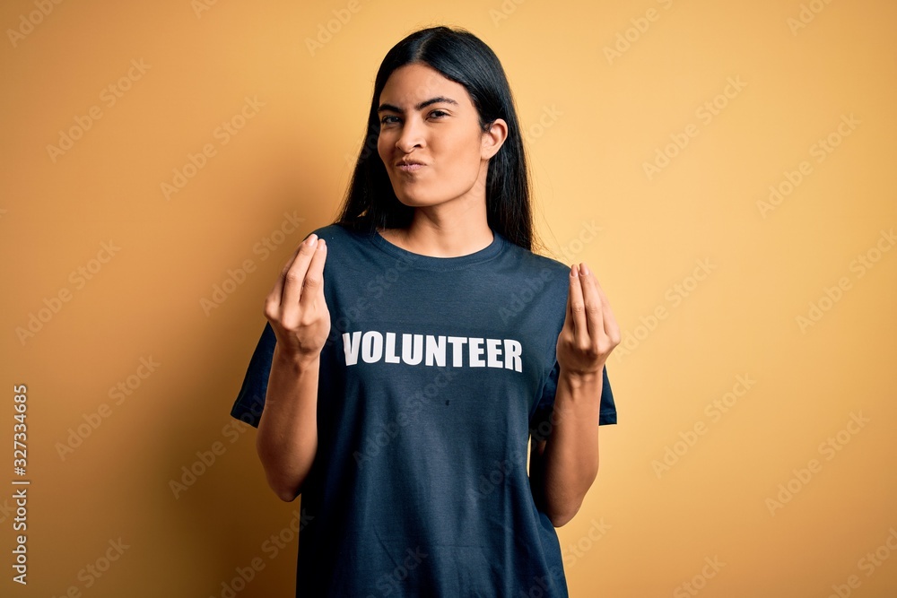 Young beautiful hispanic woman wearing volunteer t-shirt as social charity moral doing money gesture with hands, asking for salary payment, millionaire business Young beautiful hispanic woman wearing volunteer t-shirt as social charity moral doing money gesture with hands, asking for salary payment, millionaire business
