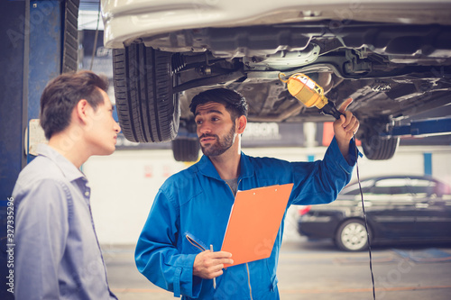 Mechanic holding clipboard with car owner in the workshop garage. Car auto services concepts