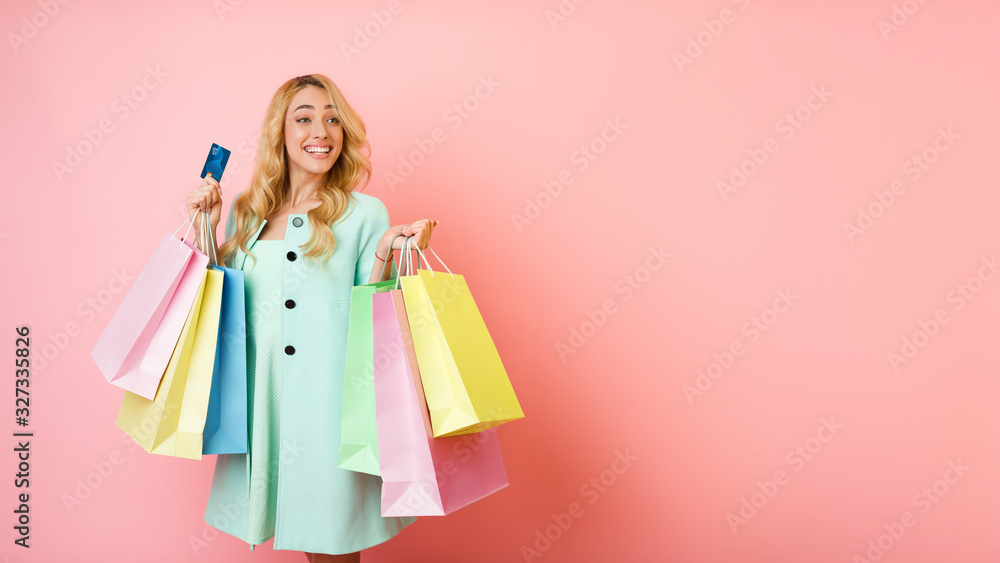 Overjoyed woman in coat holding shopping bags and credit card