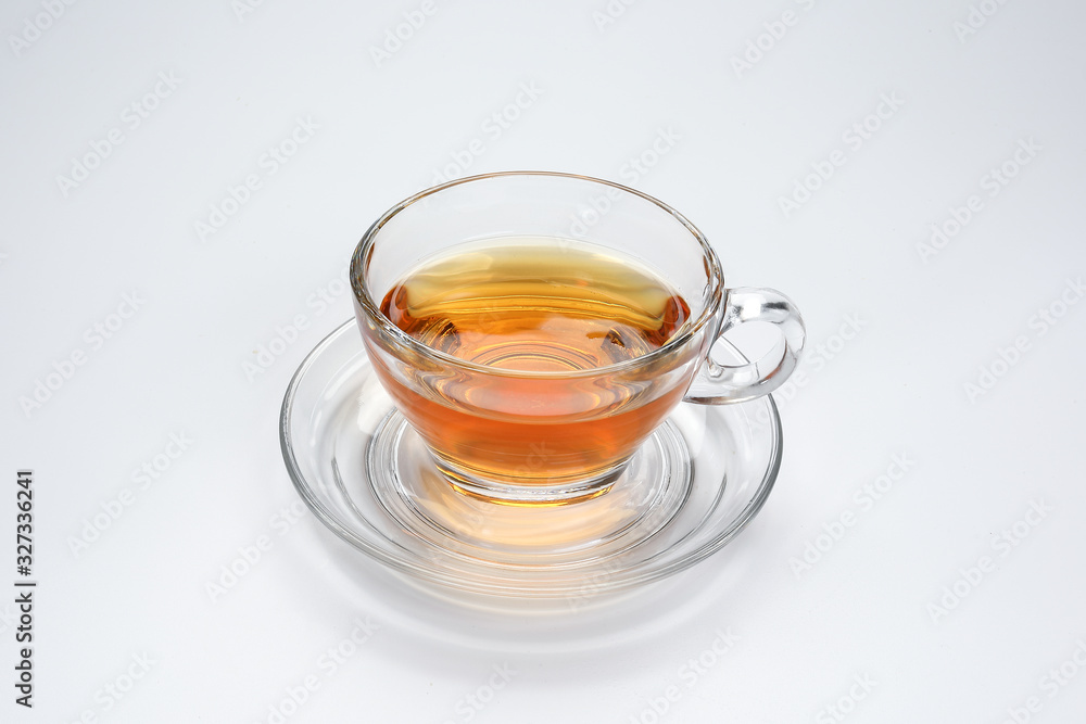 Clear licker tea in a transparent glass cup saucer on white background