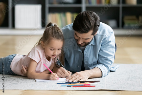 Young dad have fun drawing with little daughter