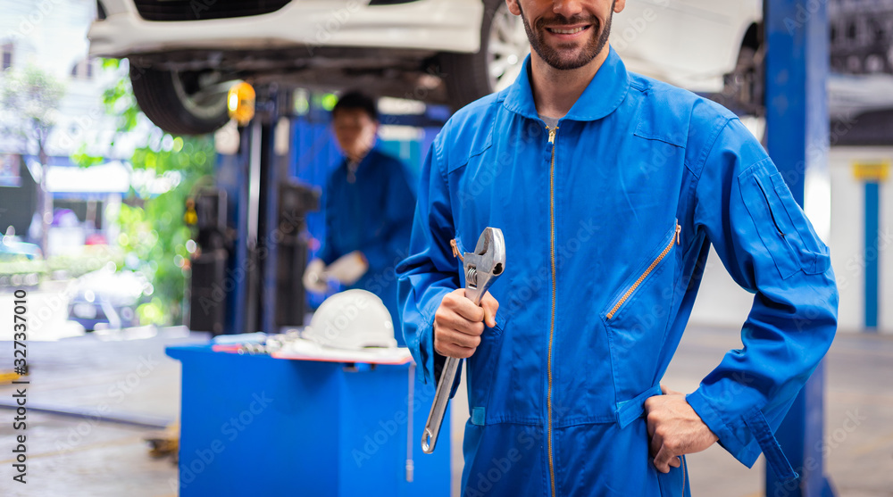 Fototapeta premium Mechanics holding wrench in the workshop garage. Auto car services concepts