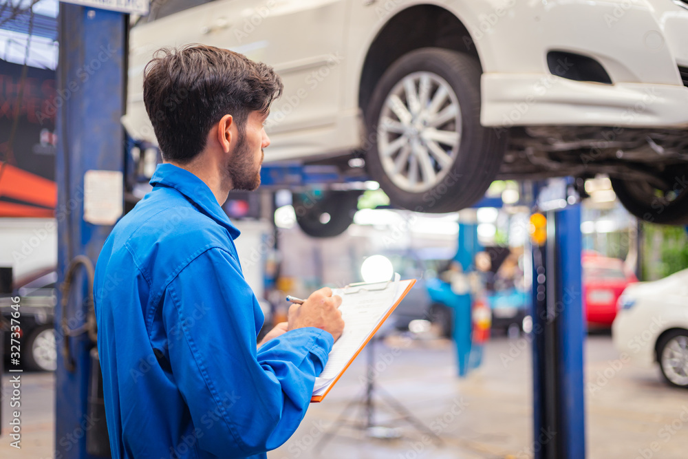 Mechanic checking car and write down in the paper on clipboard. Auto car service concepts Mechanic checking car and write down in the paper on clipboard. Auto car service concepts