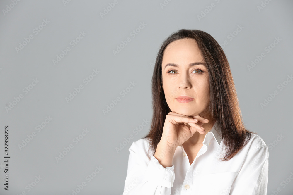 Portrait of beautiful mature woman on grey background. Space for text Portrait of beautiful mature woman on grey background. Space for text
