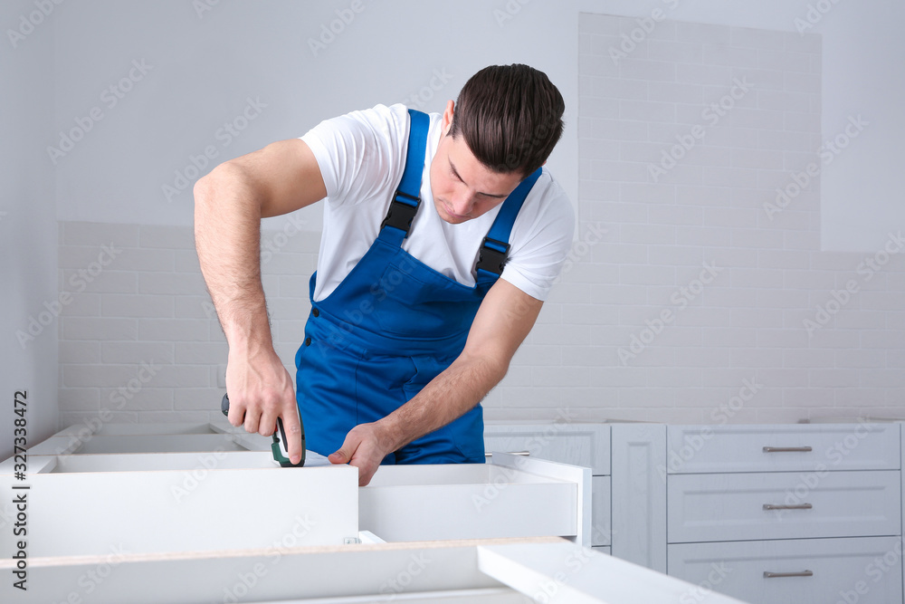 Maintenance worker installing new kitchen furniture indoors Maintenance worker installing new kitchen furniture indoors