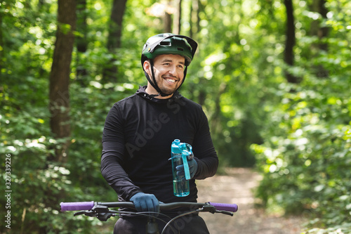 Smiling cycler carrying bottle of water, resting