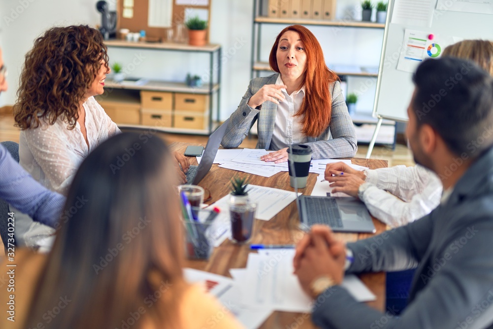 Group of business workers working together. Sitting on desk using laptop reading documents at the office Group of business workers working together. Sitting on desk using laptop reading documents at the office