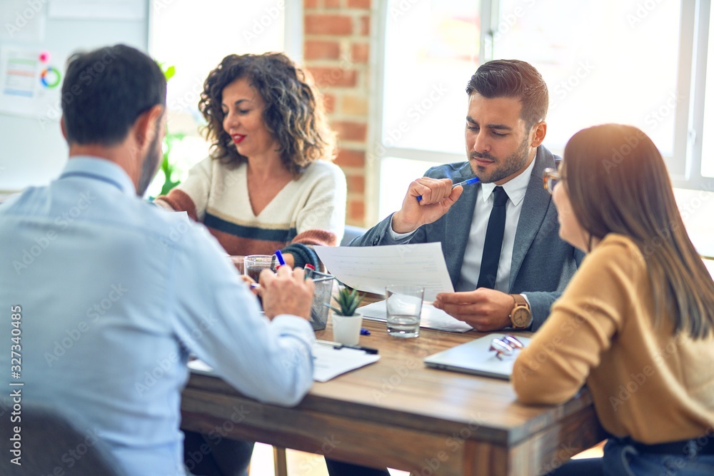 Group of business workers working together. Sitting on desk reading documents at the office Group of business workers working together. Sitting on desk reading documents at the office