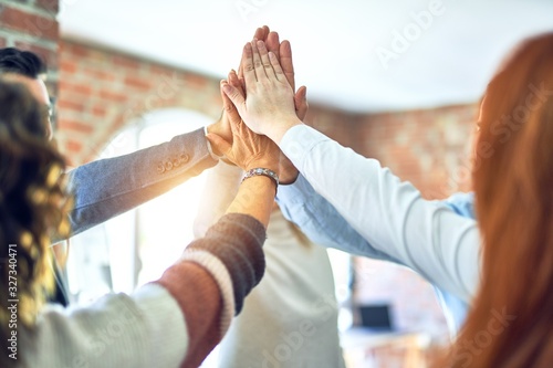 Group of business workers standing with hands together highing five at the office photo
