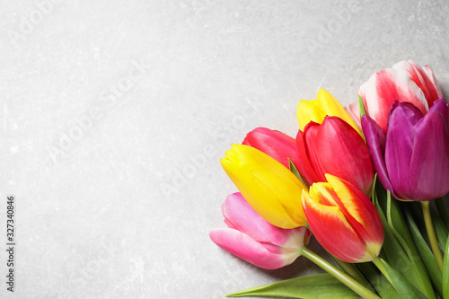 Fototapeta Naklejka Na Ścianę i Meble -  Beautiful spring tulips on light grey stone table, flat lay. Space for text