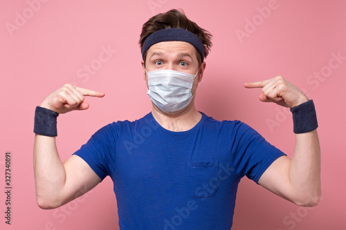 Young caucasian sportive man in a medical mask photo