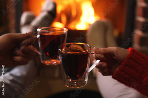 Couple with mulled wine near fireplace indoors  closeup. Winter vacation
