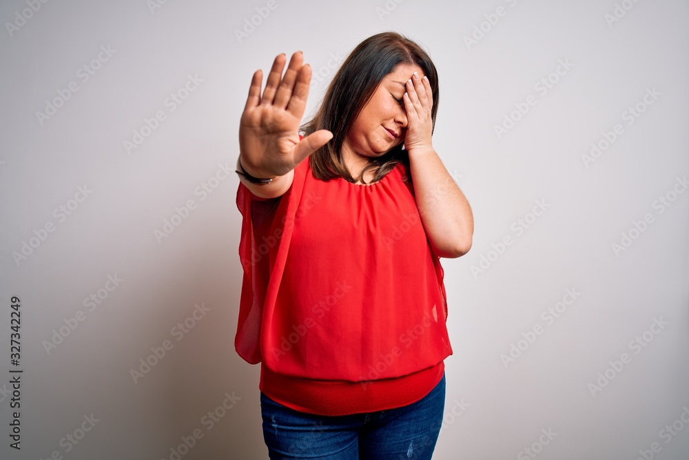 Beautiful brunette plus size woman wearing casual red t-shirt over isolated white background covering eyes with hands and doing stop gesture with sad and fear expression. Embarrassed and negative Beautiful brunette plus size woman wearing casual red t-shirt over isolated white background covering eyes with hands and doing stop gesture with sad and fear expression. Embarrassed and negative