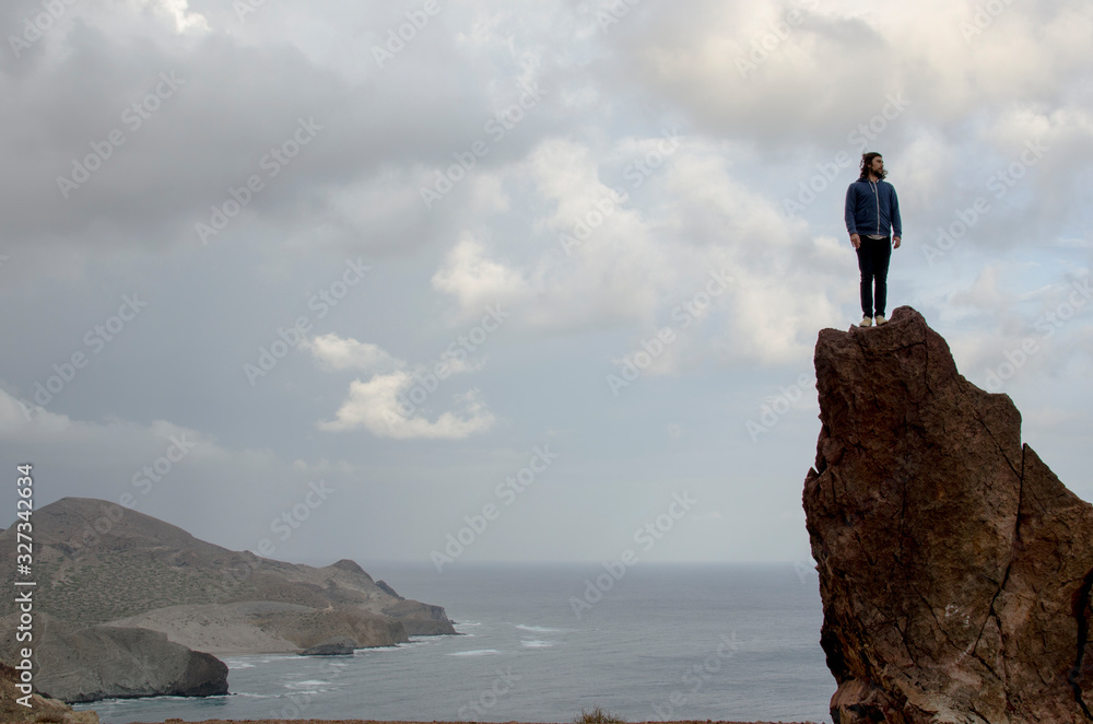 man on top of a high rock doing poses