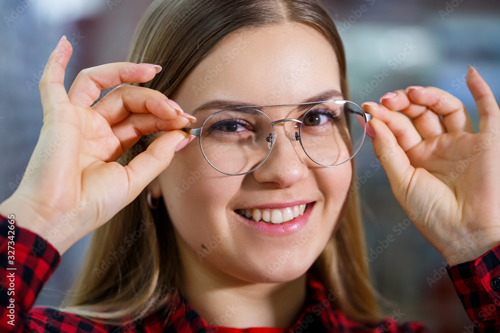 The girl in the shirt takes out and measures on herself glasses The girl in the shirt takes out and measures on herself glasses