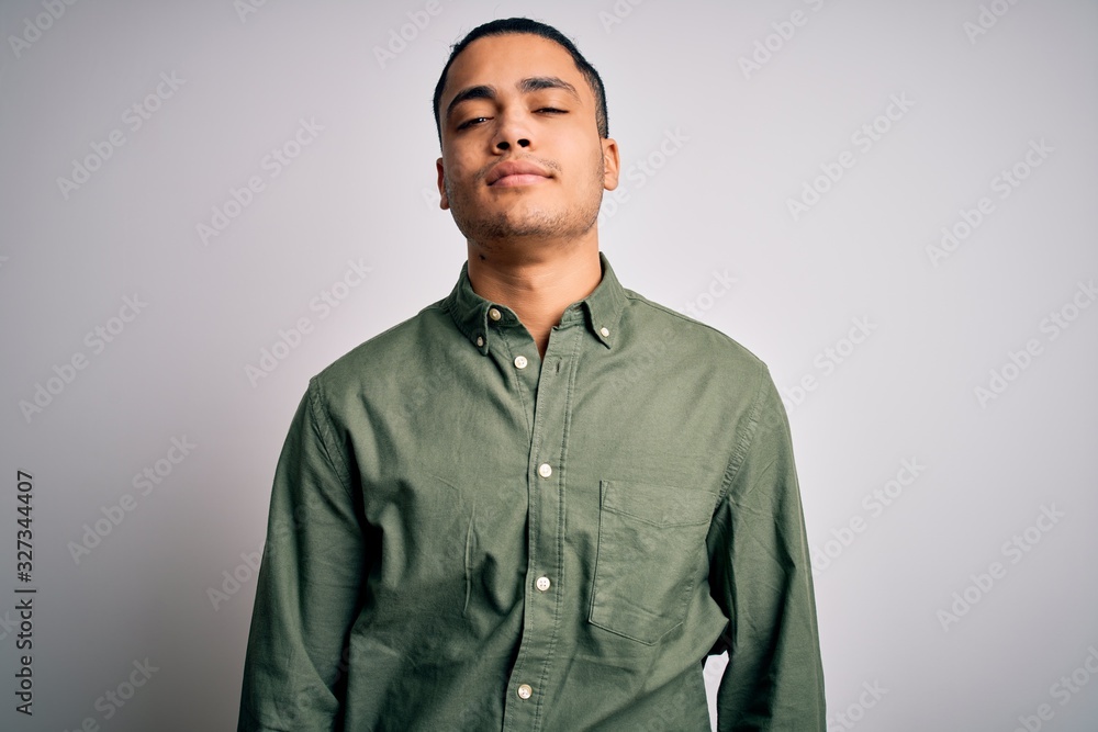 Obraz premium Young brazilian man wearing casual shirt standing over isolated white background Relaxed with serious expression on face. Simple and natural looking at the camera.