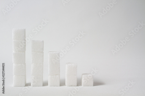 high key of five collumns made of sugar cubes with decreasing height symbolizing the need of reducing sugar consumption photo