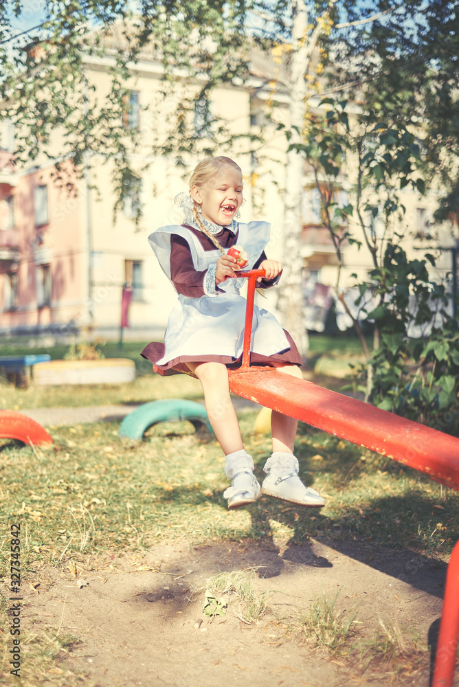 happy little girl riding on a swing. schoolgirl in uniform plays on the playground.