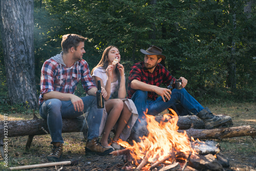 Group of happy friends roasting marshmallows on campfire. Happy young friends having picnic. Vacation weekend picnic camping and hiking. Find companion to travel and hike.