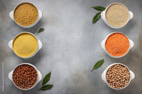 assorted cereals: bulgur, couscous, beans, quinoa, lentils, chickpeas, laurel. healthy food concept. copy space. gray concrete background, top view © Mila Naumova