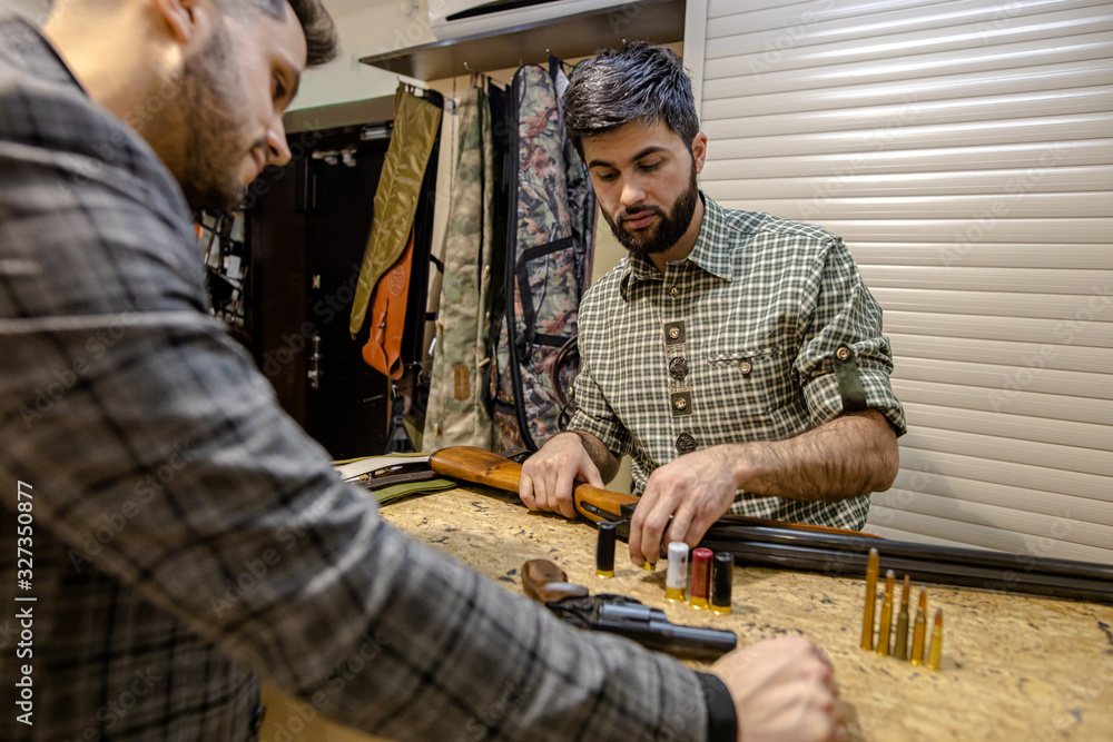 customer and salesman disassemble the rifle into parts. young guys make a deal to have firearm in store customer and salesman disassemble the rifle into parts. young guys make a deal to have firearm in store