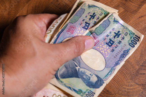 Male hands shows Japanese yen. Yen is the currency of Japan. On the Obverse side of the banknotes Hideyo Noguchi, bacteriologist from the 20th century. Paper Money from Japan. Banknote with low value photo